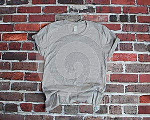 Flat lay mockup of gray tee shirt on brick background