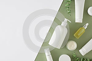 Flat lay mockup of white cosmetic bottles, cream jars, dropper bottles, eucalyptus leaves