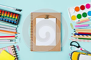 Flat lay of modern bright blue office desktop with school supplies on table around empty space for text. Top view Back to school