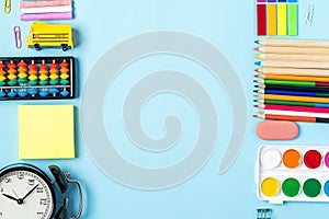 Flat lay of modern bright blue office desktop with school supplies on table around empty space for text. Top view Back to school