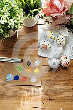 Flat lay of modern easter eggs painted. Brushes and paints with flowers and plants. Happy easter concept on a wooden background