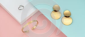 Flat lay of modern golden jewelries on pastel colors background