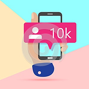 flat lay modern minimal hand holding mobile phone with new pink ten chiliad like followers social media iconon screen with shadow
