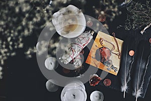 Flat lay of money attracting spell on wiccan witch altar. Illustration of a bag filled with runes, dark grey black feathers