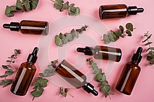 Flat lay with Natural organic cosmetics: serum, cream on pink background with green leaves. Skincare, cosmetology