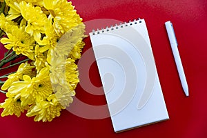 Flat lay of notebook, pen and flowers