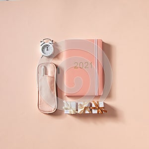 Flat lay of notepad with words Goals 2021, colorful sticky notes, o`clock, pen and pen case. Coral pink background