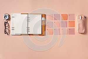 Flat lay of notepad with words Goals 2021, colorful sticky notes, o`clock, pen and pen case. Coral pink background