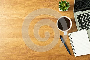 Flat lay of Office desk with laptop, and blank notepad with a coffee cup on wood table