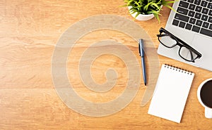 Flat lay of Office desk with laptop, and blank notepad with a coffee cup on wood table