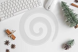 Flat lay Office desk table with computer wireless keyboard, mouse, mini Christmas tree, spices, pine cone decoration on white tab