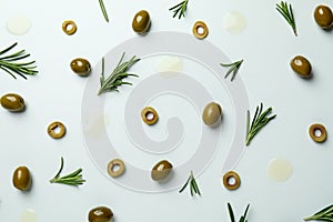 Flat lay olives, rosemary and oil spots on white background