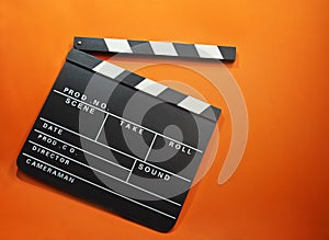 Flat lay an open film clap board with a bright orange background