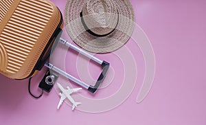 Flat lay orange suitcases and travel accessories on a pink background and travelling during covid-19 epidemic concept