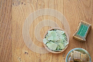 Flat lay overhead shot of an Aleppo bar soap and cuts showing its green color on a wooden background. v
