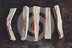 Flat lay of Palo Santo sticks from Bursera graveolens holy wood tree laid on dark brown wooden table photo