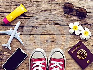 Flat lay of passport , mobile , plane model , red sneakers