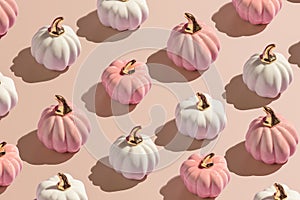 Flat lay pattern from white and pink decorative autumn pumpkins on beige background in hard light
