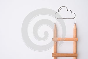 Flat lay of pencil ladder and outline cloud on white paper background copy space. Creative idea, imagination, design and education