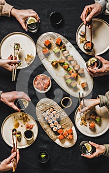 Flat-lay of people eating various sushi during japanese lockdown dinner