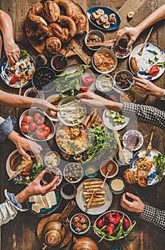 Flat-lay of peoples hands taking traditional turkish breakfast meals