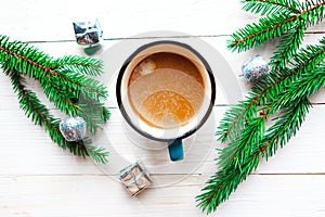 Flat lay photo with coffee cup, spruce branches and Christmas decorations on white wooden background.