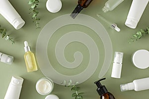 Flat lay photo of cosmetic bottles, cream jars, dropper bottles, eucalyptus leaves on pastel green background