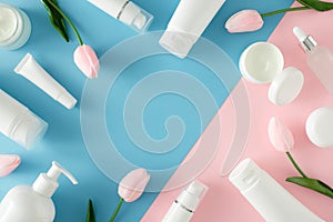 Flat lay photo of cosmetic tubes without label, cream jars, dropper bottles and spring flowers