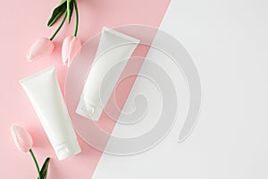 Flat lay photo of cosmetic tubes without label and spring flowers