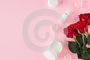 Flat lay photo of cream jar, cosmetic bottles, red roses, heart shaped candles