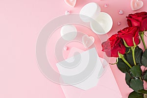 Flat lay photo of cream jars, red roses, heart shaped candles and envelope with letter