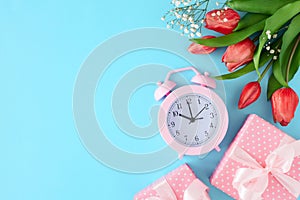 Flat lay photo of gift boxes wit silk ribbons, tulips flowers and pink alarm clock