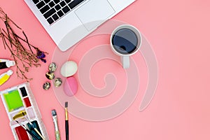 Flat lay photo of modern workplace with laptop and eggs, top view laptop background and paint set preparing for Easter on pink