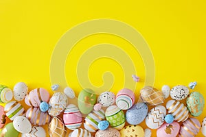 Flat lay photo of multicolored eggs and cute rabbits on yellow background