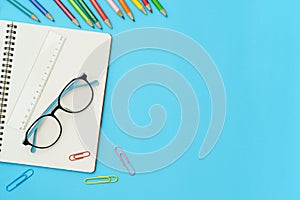 Flat lay photo of office desk with colorful pencil, Paper clip, Ruler, Note book, Glasses, Top view of the copy space