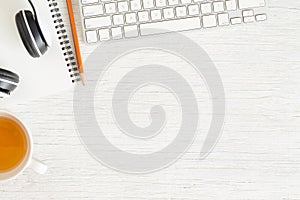 Flat lay photo of office desk with  Earphone and keyboard,Copy space on white background with notebook and pencil,  tea photo