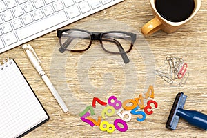 Flat lay photo of office desk with keyboard, notebook, eyeglasses and coffee cup, wooden stamp, paper clip. top view.