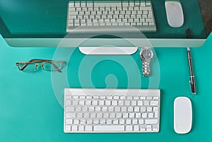 Flat lay photo of office desk with keyboard, notebook, tablet, smartphone, eyeglasses