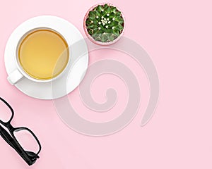 Flat lay photo of office desk with tea mug, cactus, glasses, pink background