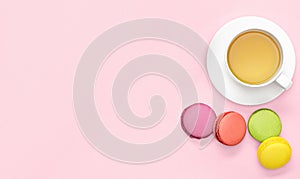 Flat lay photo of office desk with tea mug, macaroons pink background