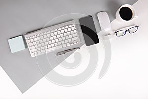 Flat lay photo of Office table with keyboard, notebook, digital tablet, mobile phone, Pencil, eyeglasses on modern two tone