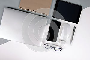 Flat lay photo of Office table with laptop computer, notebook, digital tablet, mobile phone on modern two tone background