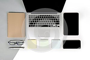 Flat lay photo of Office table with laptop computer, notebook, digital tablet, mobile phone on modern two tone background