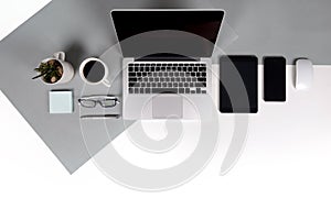 Flat lay photo of Office table with laptop computer, notebook, digital tablet, mobile phone on modern two tone background