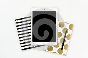 Flat lay photo of office white desk with tablet and gold notebook copy space background