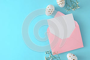 Flat lay photo of open envelope with letter, white gold eggs, gypsophila flowers