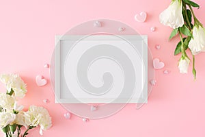 Flat lay photo of white spring flowers and hearts on pastel pink background