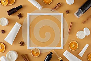 Flat lay photo of white tube, cream jars, dried orange slices and cinnamon sticks