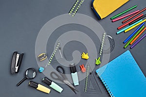 Flat lay photo of workspace desk with school accessories or office supplies on gray background.