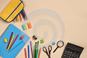 Flat lay photo of workspace desk with school accessories or office supplies on pink background.